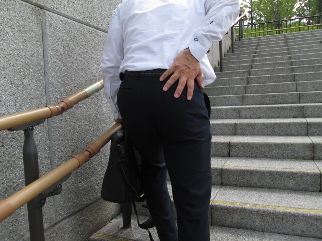 腰をおさえているスーツ姿の男性